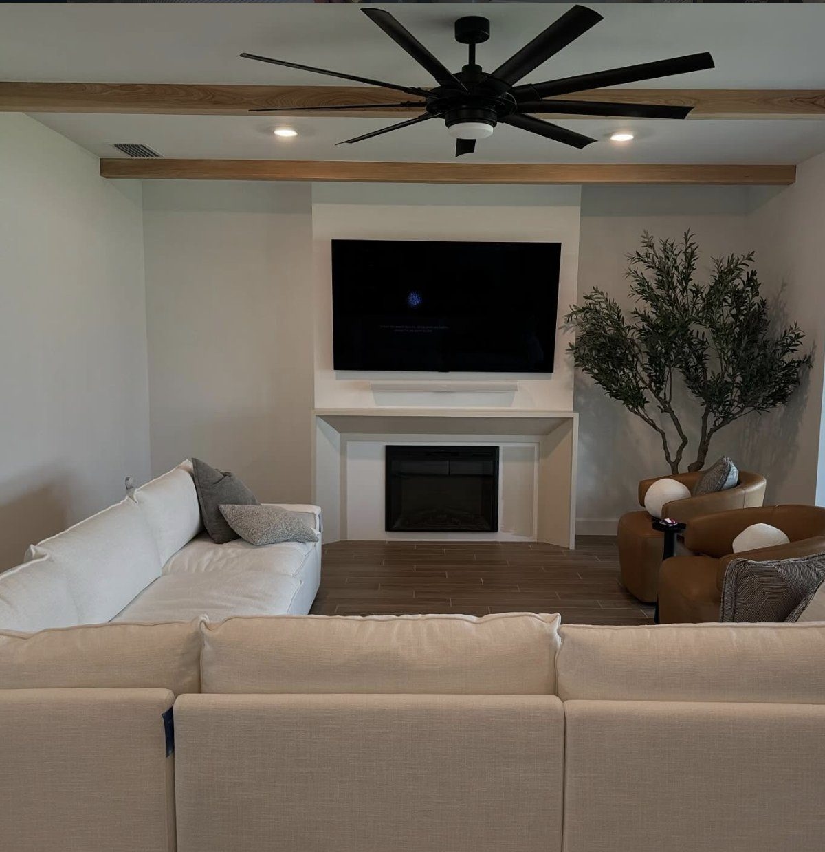 Living room fireplace wall with custom trim beneath an exposed wood beam ceiling